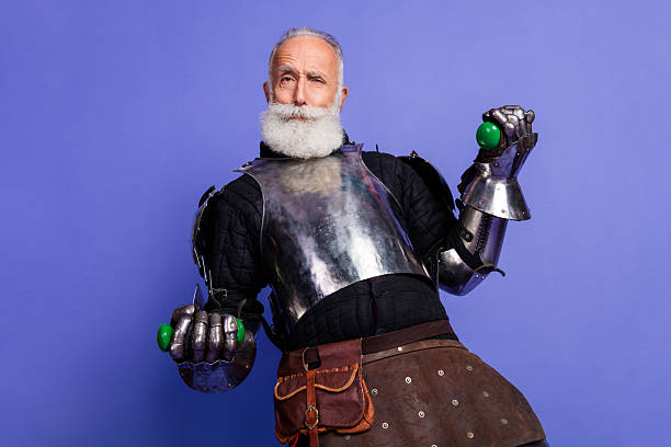 istock Elderly Man in Medieval Armor Posing Against a Purple Background with Playful Expression 2221618476