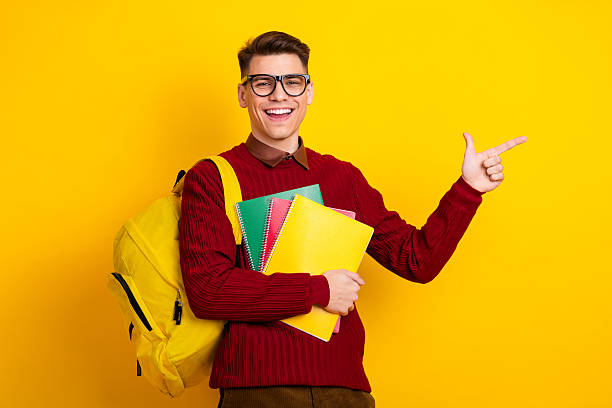 istock Cheerful Young Student Holding Notebooks and Backpack in Bright Studio Background 2221619701