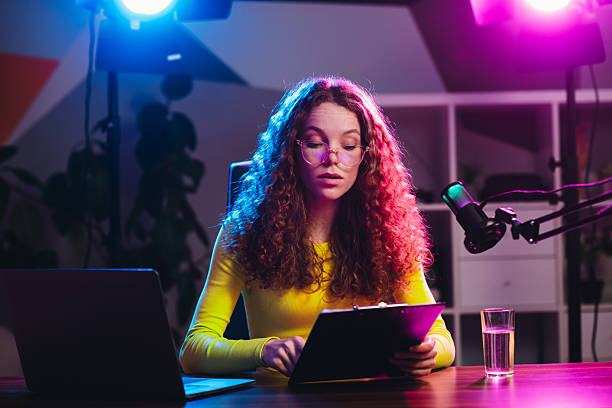 istock Popular blogger at a desk in a vibrant light setting, studying or broadcasting with digital technology and equipment 2221620573