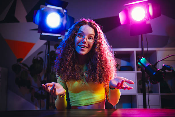 istock Young woman in a vibrant setup with neon lights using professional equipment for creating engaging digital content 2221620584