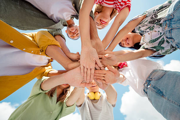 istock Happy young individuals uniting hands in celebration outdoors under a bright summer sky showcasing teamwork 2221623390