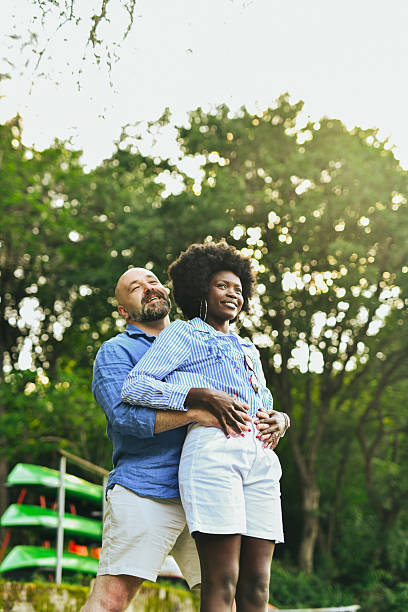 istock Interracial Couple Facing Away From Camera While Man is Hugging Girlfriend and They're Admiring the View 2221624073
