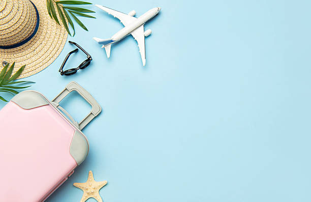istock Pink suitcase, airplane model, sunglasses and straw hat on blue background with copy space 2221626991