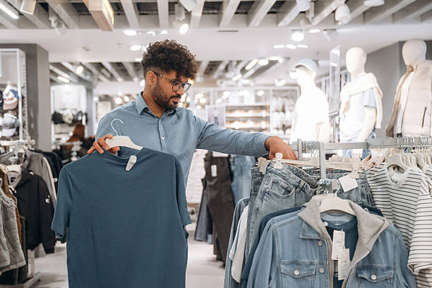 istock Sweaters section. Man customer is in the clothing store 2221632543