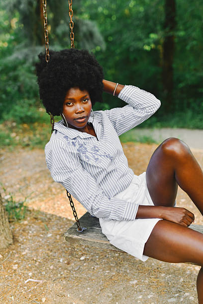 Serious Female Sitting On Hanging Swing Looking Directly At Camera With Intense Expression