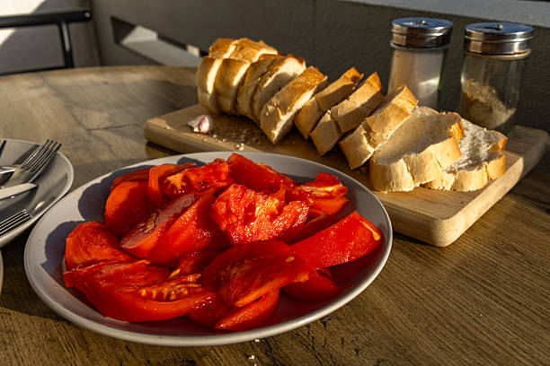 Mediterranean breakfast, red tomatoes, olive oil, fresh bread, arranged on plates on a table on the terrace