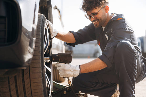 Screwdriver in hand. Mechanic is with the car outdoors stock photo