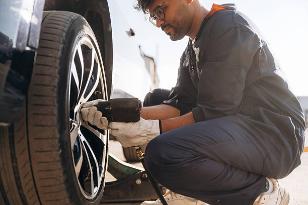 istock Sitting, side view, changing tire, using screwdriver. Mechanic is with the car outdoors 2221638736