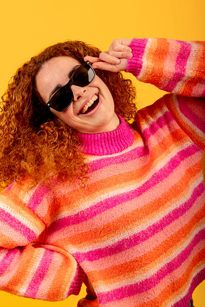 istock Redhead model smiling and touching sunglasses on yellow background 2221640538