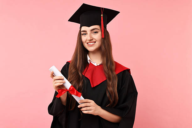 istock Happy student with diploma after graduation on pink background 2221643593