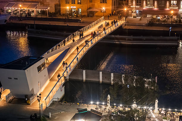 Gdansk, Poland - October 6, 2022: Bascule bridge (drawbridge) between Old Town and Olowianka Island at night, pedestrian and cycling footbridge across Old Motlawa river in historic city centre.