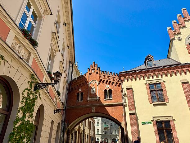 Rynek Glowy, Old Town Krakow, is surrounded by historic townhouses, St.  Mary’s Basilica, Cloth Hall,  Town Hall Tower, and Church of St. Adalbert. Rising square are Gothic Towers.