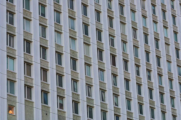 istock Building facade with multiple windows, one brightly lit, showcasing urban evening lighting 2221653686