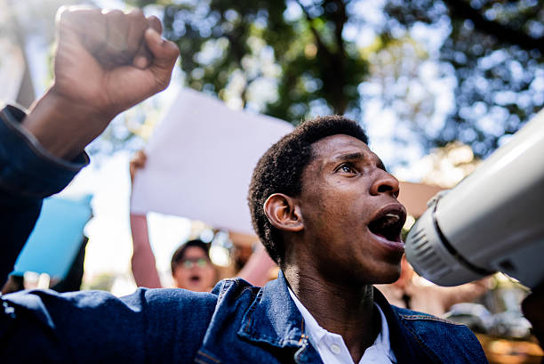 Young man protesting and screaming on megaphone outdoors