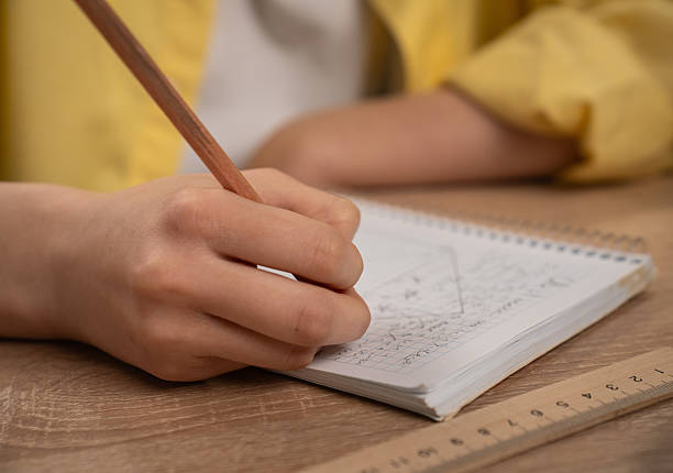 istock Student Writing in Notepad with Pencil and Ruler Nearby 2221654766