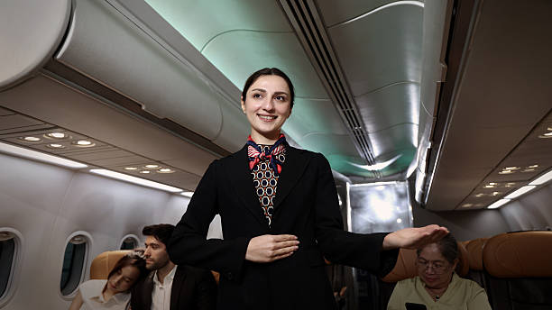 istock Air hostess. Smiling flight attendant in uniform welcomes and guides passengers aboard a modern airplane. Friendly airline staff providing professional service and comfortable travel flight experience 2221657644