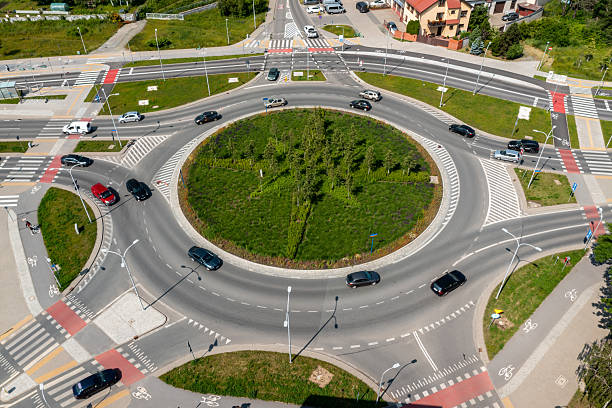 istock Large roundabout intersection with greenery and road markings surrounded by vehicles and urban roads 2221662308