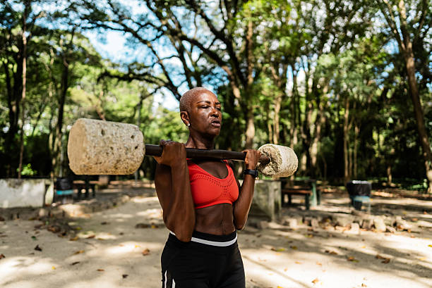 Mature woman doing biceps exercise in a outdoors gym at public park