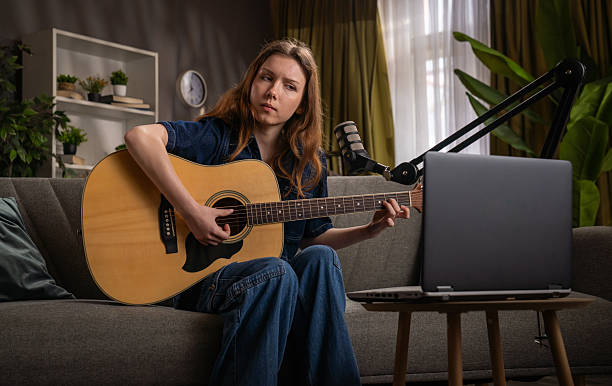 istock Young Woman Playing Guitar During Virtual Music Lesson Online 2221663400