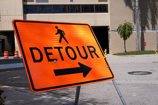 Orange pedestrian detour sign on road