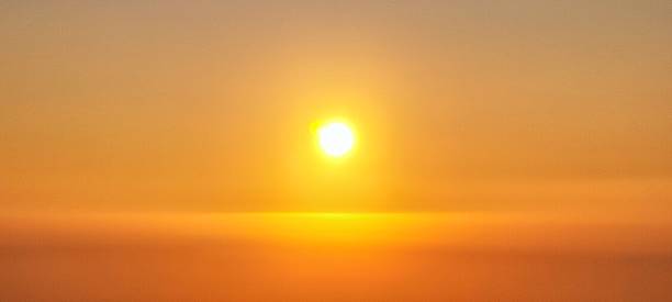 Sunrise at Stonehenge Summer Solstice, through the mist/fog with people in silhouette.