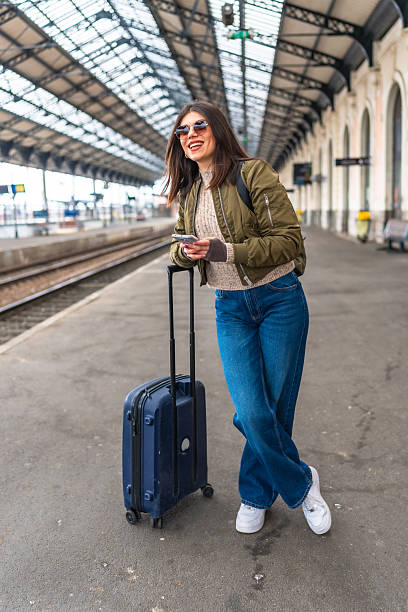 istock Young woman waiting for train and using smartphone at railway station 2221667213