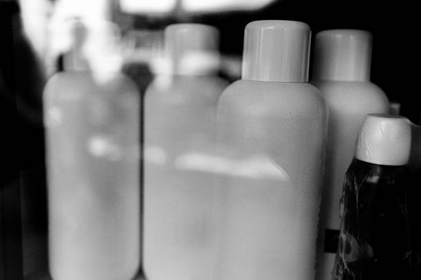 A blurred black and white photograph depicting a row of shampoo or conditioner bottles.