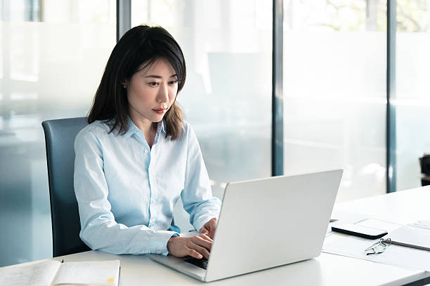 istock Thoughtful middle-aged woman using computer for financial bank work online. Mature Asian professional specialist businesswoman working on laptop pc sitting at desk in office looking at device screen 2221669883