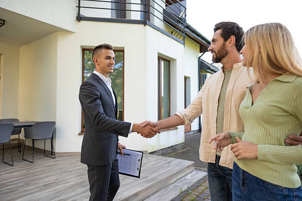 istock Pair celebrating home purchase with agent in green yard area 2221676316