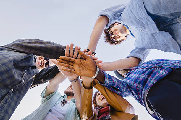 istock Diverse group of young people joining hands in circle from low angle 2221677121