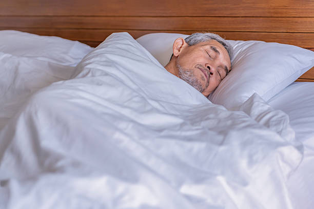 istock senior man laying comfortable under a white blanket,resting,bedtime deep sleeping in a cozy room,elderly people get enough sleep 2221678052