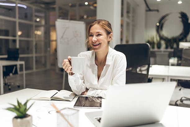 istock Businesswoman taking notes in notebook with whiteboard visible in office setting 2221691265
