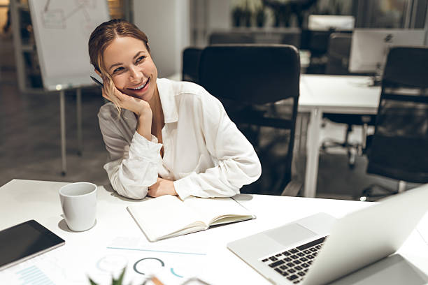 istock Businesswoman working on laptop with notebook in modern office setting at evening 2221691772