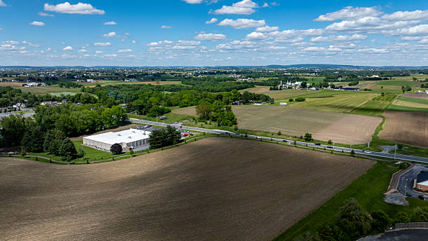 istock Expansive Rural Landscape With Fields and Modern Building Under a Bright Blue Sky 2221692196
