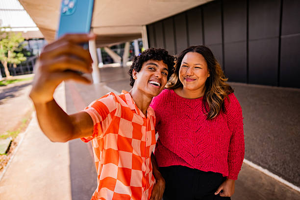 istock Young friends taking a selfie using mobile phone outdoors 2221694273