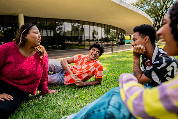 istock Friends talking sitting on grass on public park 2221694427