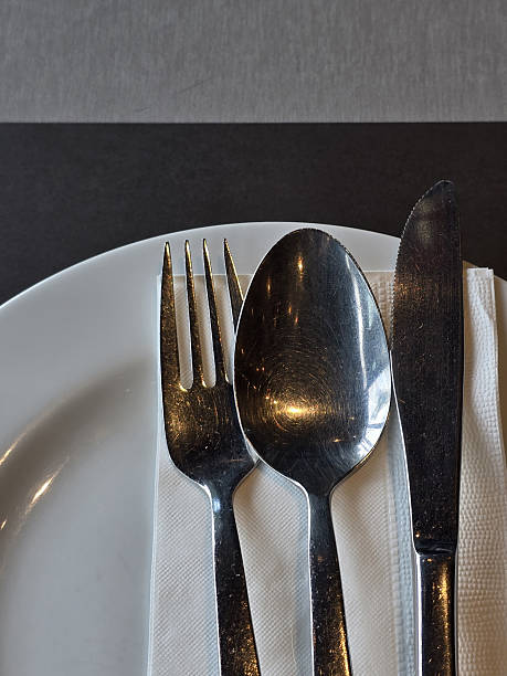 istock Elegant table setting with silver cutlery including knife, spoon, and fork on white plate, showcasing minimalist dining experience 2221695349
