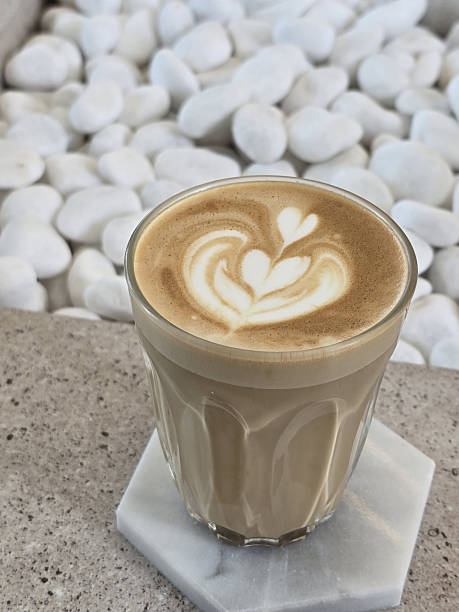 istock beautifully crafted latte with intricate foam art sits on marble coaster, surrounded by smooth white pebbles, creating serene and inviting atmosphere 2221695403