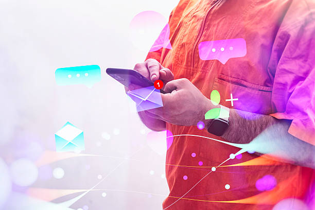 istock A man wearing a orange vest holds a smartphone displaying chat and email notifications, surrounded by vibrant digital icons. 2221696597