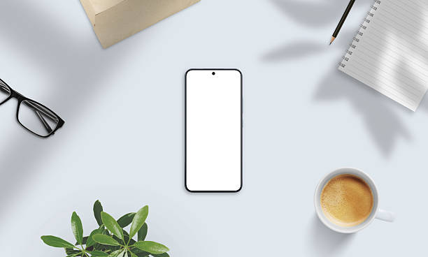 istock Smartphone mockup on soft-lit desk with coffee, glasses, notebook, and shadows. Perfect for natural presentation of apps and digital content 2221700628