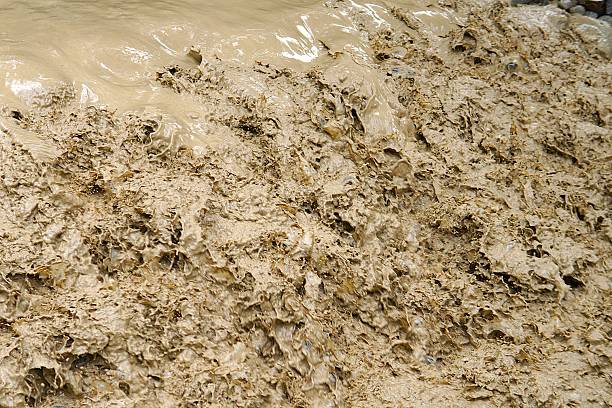 Brown river flows after rain. After heavy rains in the mountains, the mountain river turned into a muddy, fast flow. Heavy rains caused a sudden rise of water, carrying away soil.