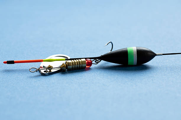 istock Fishing tackle including a lure, float, and hook on a blue background. 2221702737