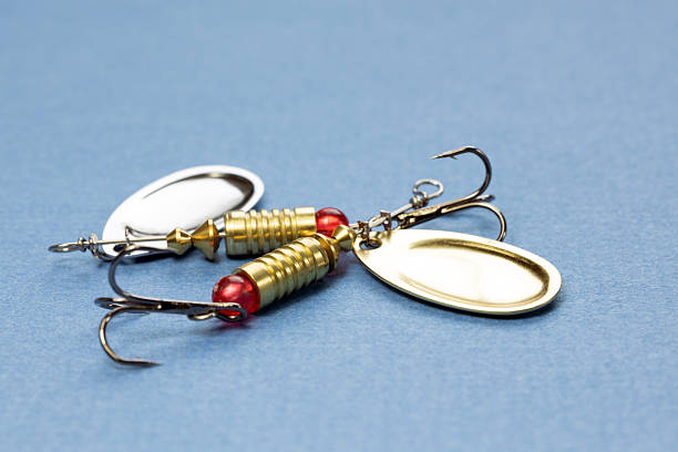Fishing lures and floats on a blue background. The image features shiny metal spoons and hooks, essential tools for anglers.
