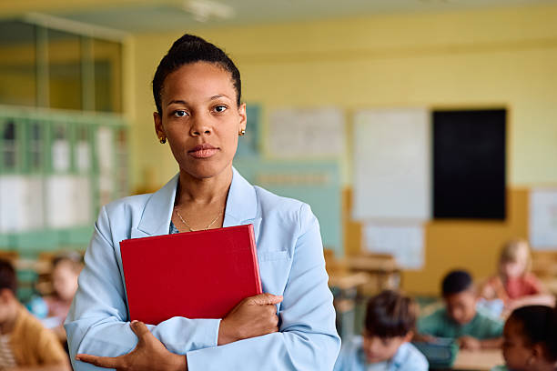 istock Black female elementary school teacher in the classroom looking at camera. 2221704323