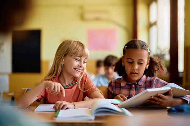 istock Happy schoolgirls learning together in the classroom. 2221704431