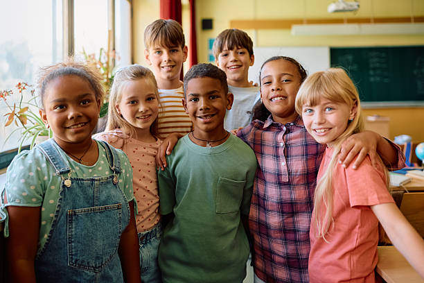 istock Group of happy elementary school classmates in the classroom looking at camera. 2221704520