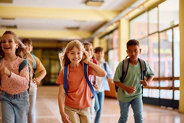 istock Happy school kids having fun while running through the hallway. 2221704654