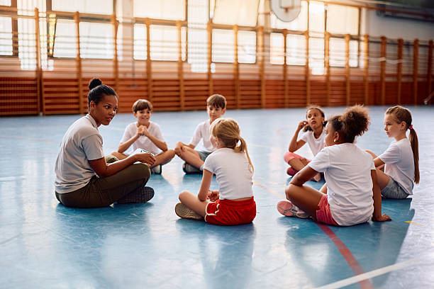 istock Black physical education teacher communicating with her students at school gym. 2221704846
