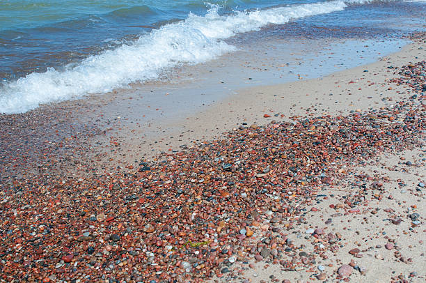 Pebbles and sand at seashore and sea waves