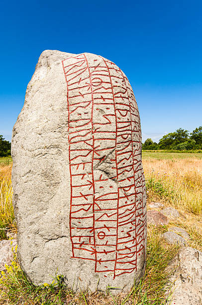 istock Ancient runestone with carvings stands in a grassy field under a clear blue sky 2221707711